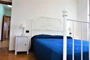 een slaapkamer met een wit bed met een blauwe sprei bij Apartment La Coccinella in Riva del Garda