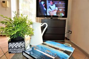 een tafel met een boek en een vaas en een tv bij Apartment La Coccinella in Riva del Garda