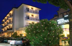 a large white building with cars parked in front of it at Hotel Arizona in Lido di Jesolo