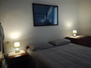 a bedroom with a bed with two lamps and a tv on the wall at Casa Gemma in Diano Marina