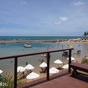 uma praia com guarda-sóis e pessoas na água em Nannai Térreo Porto de Galinhas 06 em Porto de Galinhas