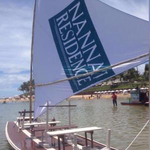 a boat with a sail in the water on a beach at Nannai Térreo Porto de Galinhas 06 in Porto De Galinhas