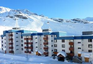 un edificio nella neve con montagne innevate di L'Olympic - T2 - Pied des pistes - 40 m2 - WIFI a Val Thorens