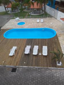 una piscina con tumbonas blancas en una terraza en Vila das Gaivotas, en Florianópolis