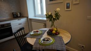 a table with a vase of flowers and fruit on it at Unique Valdemara street Studio in Riga