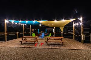 una terraza con 2 mesas de picnic y luces por la noche en Matlacha Tiny Village en Matlacha