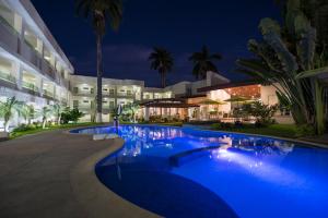 a swimming pool in front of a building at night at Hotel Palace Inn in Tuxtla Gutiérrez