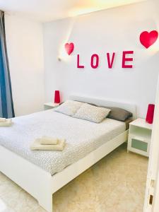 een slaapkamer met een bed met een liefdesbord aan de muur bij New Canela Apartment in Costa Teguise