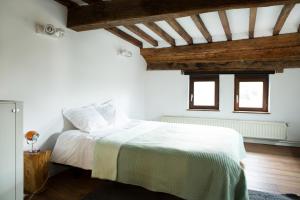 Un dormitorio con una cama con sábanas blancas y techos de madera. en Maison Sainte-Marguerite en Lieja