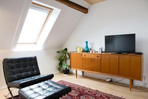 a living room with a tv and a leather chair at Maison Sainte-Marguerite in Liège