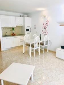コスタ・テギセにあるNew Canela Apartmentの白いキャビネット、テーブルと椅子付きのキッチンが備わります。