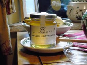 un barattolo di miele su un piatto su un tavolo di Pwllgwilym B & B a Builth Wells