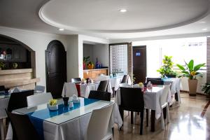 a dining room with white tables and chairs at Hotel Ingenio Reina Isabel in Cali