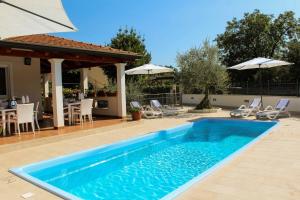 a swimming pool in a yard with chairs and an umbrella at Villa Zare in Poreč