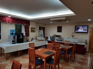 een eetkamer met tafels en stoelen en een keuken bij Hotel Camargo in Igollo