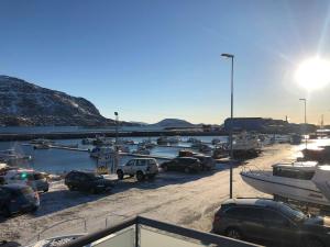 ein Parkplatz mit Autos und Booten in einem Yachthafen in der Unterkunft Kang Apartment in Nuuk