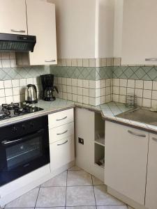 Una cocina con gabinetes blancos y un horno de estufa. en Le Saint-Rémy, en Épernay 15 fotos más