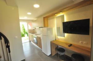 a kitchen with a refrigerator and a tv on the wall at Tassos Apartments in Acharavi