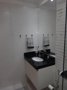 Baño blanco con lavabo y espejo en Le Bon Vivant Residential, en Arraial do Cabo