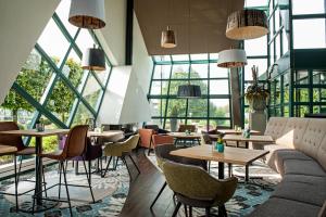 un restaurante con mesas, sillas y ventanas en Best Western Hotel Nobis Eindhoven-Venlo A67, en Asten