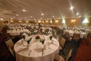 un salón de banquetes con mesas y sillas blancas en Motel le Phare, en Plessisville