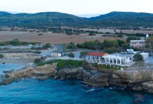 una vista aerea di una casa su un'isola rocciosa in acqua di Theresa Hotel at Karpaz Peninsula a Ayia Trias