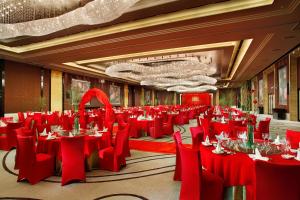 un salón de banquetes con mesas rojas y sillas rojas en Mels Weldon Dongguan Humen en Dongguan