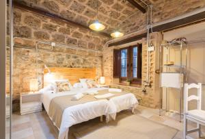 a bedroom with a large bed and a stone wall at Villa Amalia Suites Malaga in Málaga