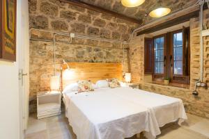 Villa Amalia Suites Malaga في مالقة: غرفة نوم بسرير كبير في جدار حجري