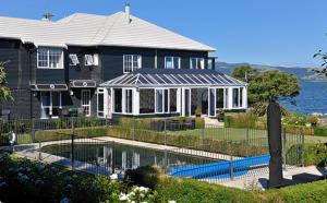 a house with a swimming pool in front of it at Black Swan Lakeside Boutique Hotel in Rotorua