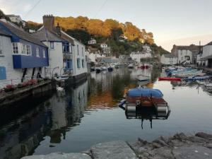 a boat is docked in a river next to houses at The House on the Props in Polperro
