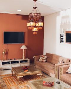 a living room with a couch and a tv at Résidence Le Ruisseau in Tozeur