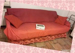 a red couch with a box on top of it at Fere Du Muin Rosso - Red Apartment in Albisola Superiore