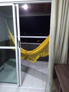a hammock on a balcony with a view of the city at Verano Praia Ponta Negra AP 1401 in Natal