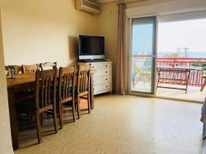 a dining room with a television and a table and chairs at Apartamento in El Perelló