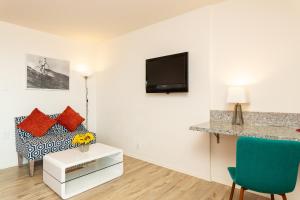 a living room with a couch and a tv on a wall at The Sea View Inn At The Beach in Manhattan Beach