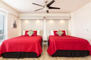 2 camas en una habitación con sábanas rojas y ventilador de techo en The Sea View Inn At The Beach, en Manhattan Beach