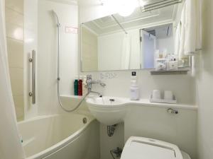 a bathroom with a sink and a toilet and a mirror at APA Hotel Ikebukuro Eki Kitaguchi in Tokyo