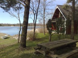 Kapteni Holiday House في Paatsalu: مقعد خشبي أمام منزل بجوار بحيرة