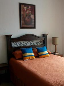 a bedroom with a bed with orange sheets and blue pillows at Habitaciones Eco-Terrazas in Guatemala