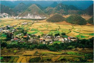 a town in a field with mountains in the background at Huyen Tram Guesthouse in Dồng Văn
