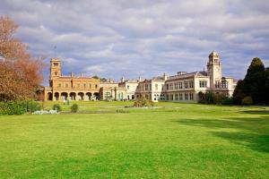 a large building with a clock tower in the middle of it at Lancemore Mansion Hotel Werribee Park in Werribee