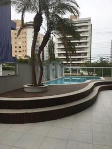 a palm tree sitting next to a swimming pool at APTO Aconchegante Praia de Palmas 01 in Governador Celso Ramos