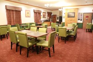 a dining room with tables and green chairs at Horizon Inn & Suites in West Point