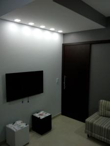 Zimmer mit einem TV, einem Sofa und einer Tür in der Unterkunft Residencial Aquidabã in Angra dos Reis