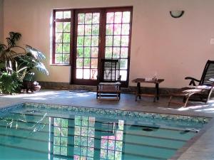 a swimming pool with chairs and a table in a room at Weavers' Cottage in Gordonʼs Bay