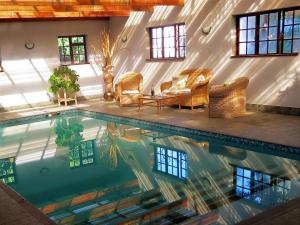 a pool in a house with chairs and a table at Weavers' Cottage in Gordonʼs Bay