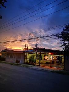 a building on a street with a sunset in the background at Hostel Pura Vida en Liberia in Liberia