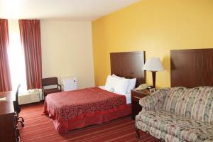 a hotel room with a bed and a couch at Days Inn by Wyndham Walcott Davenport in Walcott