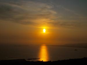 a sunset over the water with the sun in the sky at Niko Studios in Lassi